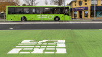 green bus drives down a road