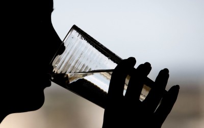 A person takes a drink from a glass of water.